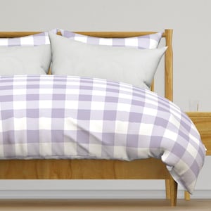Puede incluir: Una funda nórdica a cuadros de color lavanda y blanco sobre un marco de cama de madera. La funda nórdica está hecha de tela suave y transpirable, perfecta para cualquier dormitorio.