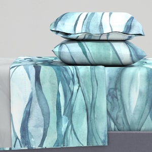 May include: A teal and blue watercolor patterned bedding set with two matching pillowcases. The bedding features a flowing, abstract design.