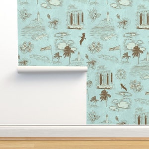 May include: A light blue wallpaper with a repeating pattern of brown illustrations. The illustrations include palm trees, lighthouses, cars, birds, and flowers. The wallpaper has a textured, linen-like appearance.