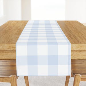 May include: A light blue and white checkered table runner. The runner is on a wooden table.