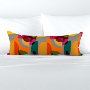 May include: A long lumbar pillow with a geometric pattern featuring overlapping circles in shades of orange, yellow, red, pink, green, and blue on a gray background.