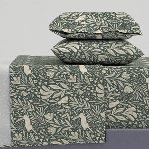 Puede incluir: Un juego de cama estampado en verde y blanco con un diseño floral y conejos blancos. El juego incluye una sábana plana, una sábana bajera y dos fundas de almohada.