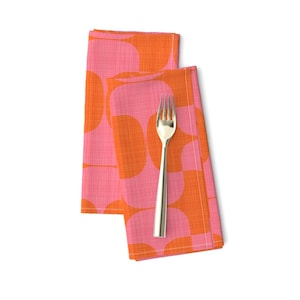 Könnte beinhalten: Zwei zusammen gefaltete Stoffservietten mit pinkfarbenem und orangefarbenem Muster, darauf eine goldene Gabel.