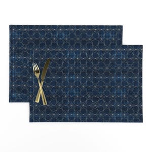 May include: Two blue placemats with a white geometric pattern. The placemats are made of a textured fabric and have a subtle sheen.