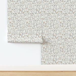 May include: A roll of wallpaper featuring a repeating pattern of hand-drawn dog illustrations in black outlines on a white background. Some dogs have small brown spots or patches on their ears or bodies, creating a dense, continuous canine motif.