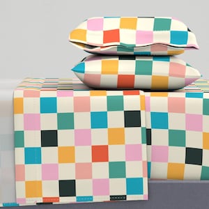 May include: A set of bedding with a checkered pattern in shades of pink, blue, green, yellow, and black. The bedding includes a fitted sheet, flat sheet, and two pillowcases.