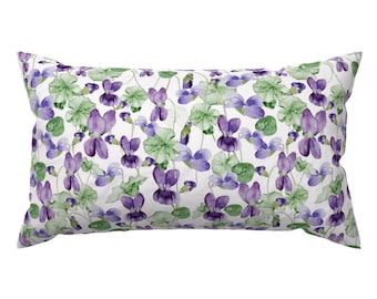 May include: Rectangular pillow with a white background and a repeating pattern of purple violets and green leaves. The watercolor design features detailed floral elements, creating a botanical theme. The pillow is a decorative home accent.