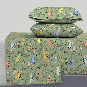 May include: A green dinosaur bedding set with a fitted sheet, flat sheet, and two pillowcases. The bedding features a repeating pattern of colorful dinosaurs on a green background.