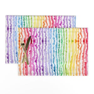 Könnte beinhalten: Zwei regenbogenfarbene Tischsets mit weißem Hintergrund. Die Streifen bestehen aus Aquarellfarbe und haben eine wellige Textur.