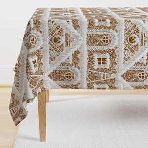 May include: A white tablecloth with a gingerbread house pattern. The houses are brown and have white icing details. The tablecloth is perfect for a holiday dinner.
