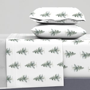 May include: White bedding with a repeating pattern of green watercolor pine trees. Two white pillowcases with the same pine tree pattern are stacked on top of the bedding.