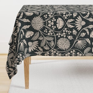 Könnte beinhalten: Eine schwarze Tischdecke mit einem weißen Blumenmuster. Die Tischdecke ist aus einem weichen, strapazierfähigen Stoff gefertigt und zeigt ein sich wiederholendes Muster aus Blumen, Blättern und Ranken.