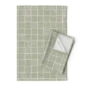 Può includere: Un set di due canovacci da cucina con motivo verde salvia e bianco. Gli asciugamani presentano un motivo a griglia ripetuto di tratti di pennello verticali e orizzontali. L'interno dell'asciugamano piegato è bianco. Gli asciugamani sono in materiale morbido.