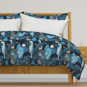 May include: A blue and grey duvet cover featuring a winter forest scene with deer, trees, and houses. The pattern is repeated across the duvet cover.