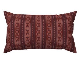 May include: A rectangular pillow with a brown and orange geometric pattern. The pattern features stripes and dots.