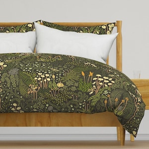 May include: A green duvet cover with a floral pattern featuring mushrooms, ferns, and other plants. The duvet cover is on a wooden bed frame with white pillows.