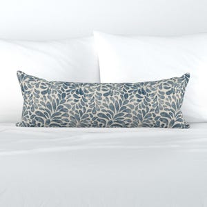 May include: A long, rectangular lumbar cushion featuring a repeating pattern of dark blue, watercolour-style leaf or petal shapes on a cream-coloured background. The cushion has a structured, elongated form with piped edges and a consistent, dense print.
