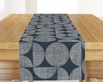 Könnte beinhalten: Ein dunkelblauer Tischläufer mit einem weißen geometrischen Muster aus Kreisen und Halbkreisen.