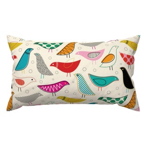 Puede incluir: Una almohada rectangular con fondo blanco y un patrón repetitivo de pájaros estilizados de colores. Los pájaros son de varios colores, incluyendo rojo, azul, verde, amarillo, rosa y negro.