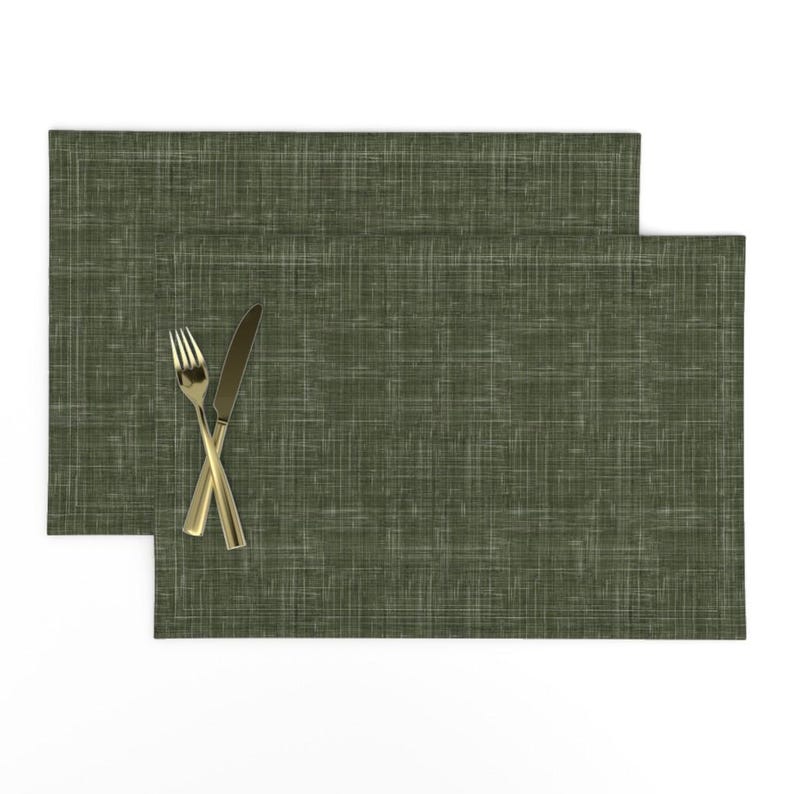 May include: Two green placemats with a subtle woven texture. A gold fork and knife are placed on top of the placemats.