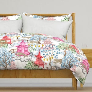 May include: A duvet cover featuring a white background with a repeating pattern of pink pagodas, brown bridges, blue trees, and spotted leopards. The design includes yellow lanterns and gray cloud-like shapes scattered across the fabric surface.