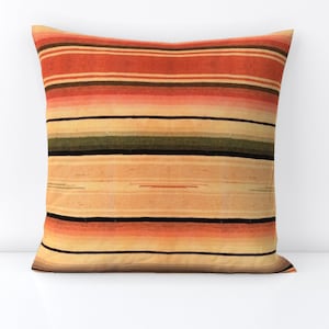 May include: A striped throw pillow with a cream background and orange, red, black, and green stripes.