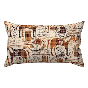 May include: Rectangular decorative pillow with a repeating pattern of equestrian equipment in shades of brown and cream. The design includes horses, riding boots, helmets, and ropes, creating a rustic, country-themed aesthetic.