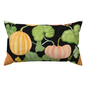 Könnte beinhalten: Ein schwarzes Lendenkissen mit einem sich wiederholenden Muster aus orangefarbenen und rosafarbenen Kürbissen mit grünen Blättern.