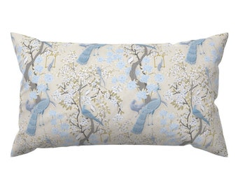May include: A rectangular throw pillow with a cream background and a repeating pattern of blue peacocks and white flowers. The pillow is made of a soft, textured fabric.