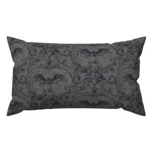 May include: A gray pillow with a black and white pattern of bats, spiderwebs, and flowers. The pattern is a repeating design.