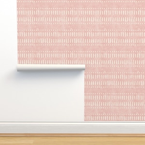 Puede incluir: Un rollo de papel tapiz rosa con un patrón geométrico blanco. El papel tapiz está parcialmente desenrollado, revelando el patrón.