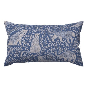 May include: A blue throw pillow with a white pattern of leopards and leafy branches.