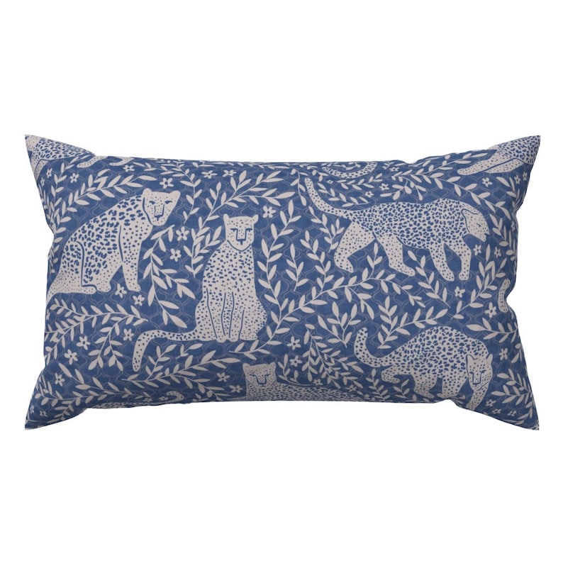 May include: A blue throw pillow with a white pattern of leopards and leafy branches.