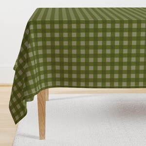 May include: A green and white checkered tablecloth with a subtle sheen. The tablecloth is draped over a table with wooden legs.