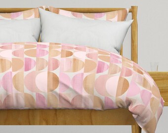 May include: A pink and brown geometric patterned duvet cover with a white background. The duvet cover is on a wooden bed frame with two white pillows.