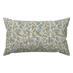May include: Rectangular pillow with a floral pattern. The design features light blue flowers, green leaves, and small blue berries on a cream-colored background. The pillow is a decorative item.