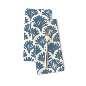 May include: Two blue and white patterned cloth napkins folded together with a silver fork on top.
