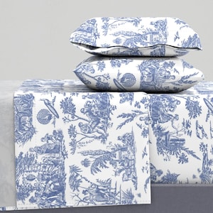 May include: A white and blue patterned bedding set with a blue and white patterned pillowcase. The bedding features a toile pattern with a repeating design of people and trees.