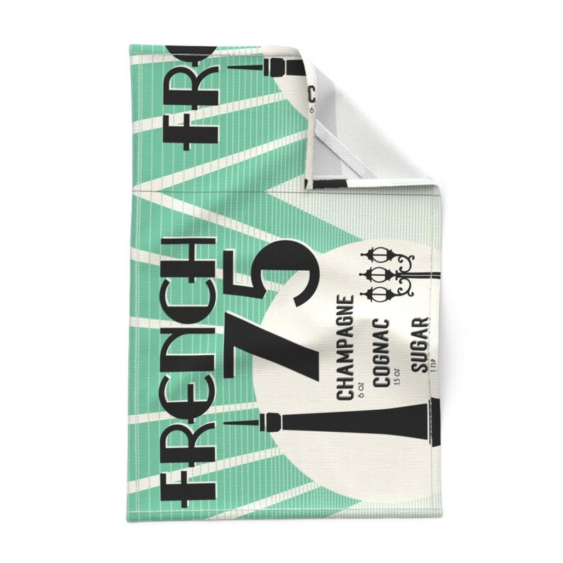 May include: A teal and white kitchen towel with the text "French 75" in black. The towel also includes the ingredients for the cocktail: 6 oz Champagne, 1 oz Cognac, and 1/2 oz Sugar.
