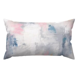 May include: A rectangular throw pillow with an abstract design featuring shades of pink, blue, and gray. The pillow has a white background with brushstrokes of color.