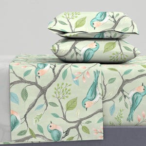 May include: A green and blue bedding set featuring a bird and branch design. The set includes a flat sheet, fitted sheet, and two pillowcases.