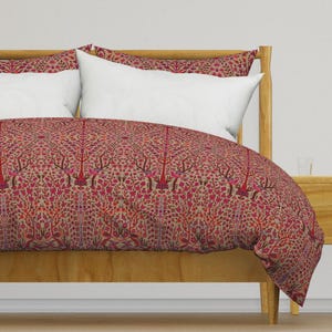 Puede incluir: Una funda nórdica con estampado rojo y marrón con un diseño floral. La funda nórdica está sobre un marco de cama de madera con almohadas blancas.