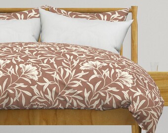 May include: A brown duvet cover with a white floral pattern. The duvet cover is on a bed with a wooden headboard and two white pillows.