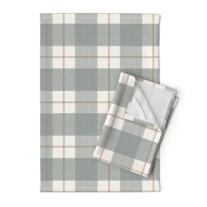 May include: A set of two kitchen towels with a plaid pattern in shades of gray and beige. The towels are folded and displayed on a white background.