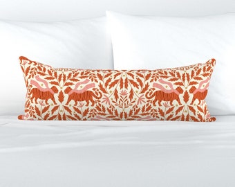 May include: A long lumbar cushion with a cream background and a repeating pattern of orange tigers, pink ribbons, and gold stars. The pattern is surrounded by a border of orange leaves.