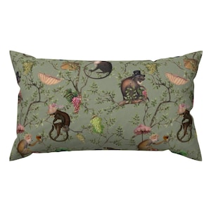 May include: A green throw pillow with a repeating pattern of monkeys wearing hats and holding teacups. The monkeys are sitting on branches with green leaves and pink flowers.