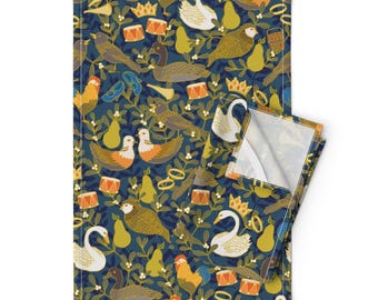May include: A teal blue kitchen towel with a repeating pattern of gold, orange, and white birds, pears, crowns, and drums. The pattern is on a dark blue background.