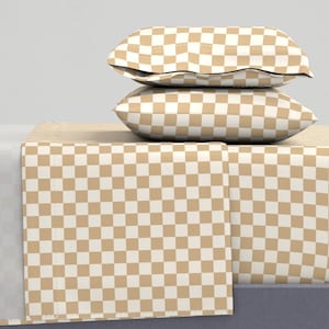May include: A tan checkered fitted sheet with two tan checkered pillowcases stacked on top of it.
