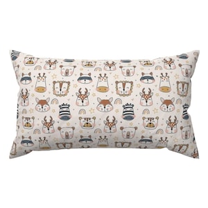 Könnte beinhalten: Ein weißer Kissenbezug mit einem sich wiederholenden Muster aus Tiergesichtern. Die Tiere umfassen ein Reh, ein Zebra, einen Bären, einen Waschbären und einen Löwen. Das Muster ist in Braun-, Schwarz-, Weiß- und Grautönen gehalten.