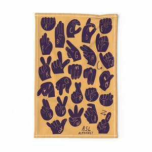 May include: A yellow kitchen towel with a black and white illustration of the American Sign Language alphabet. The towel has the text "ASL Alphabet" printed on it.
